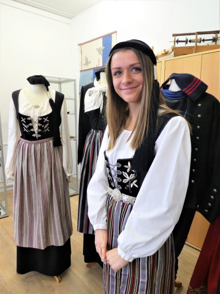 woman wears upphultur costume, including cap and belt
